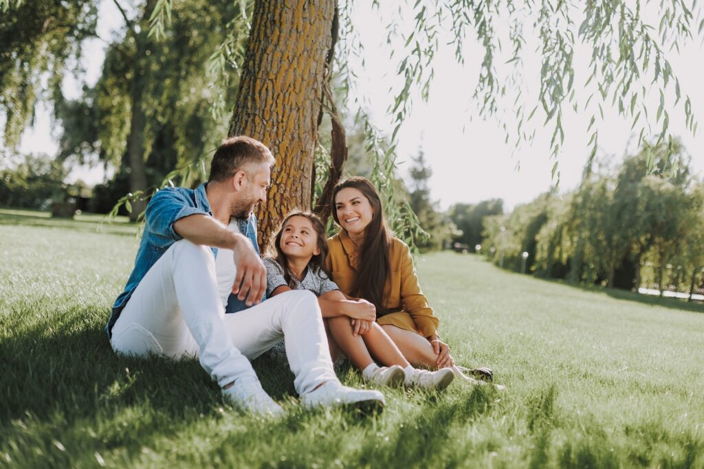 Image of a happy family sitting at the base of a tree communicating with each other